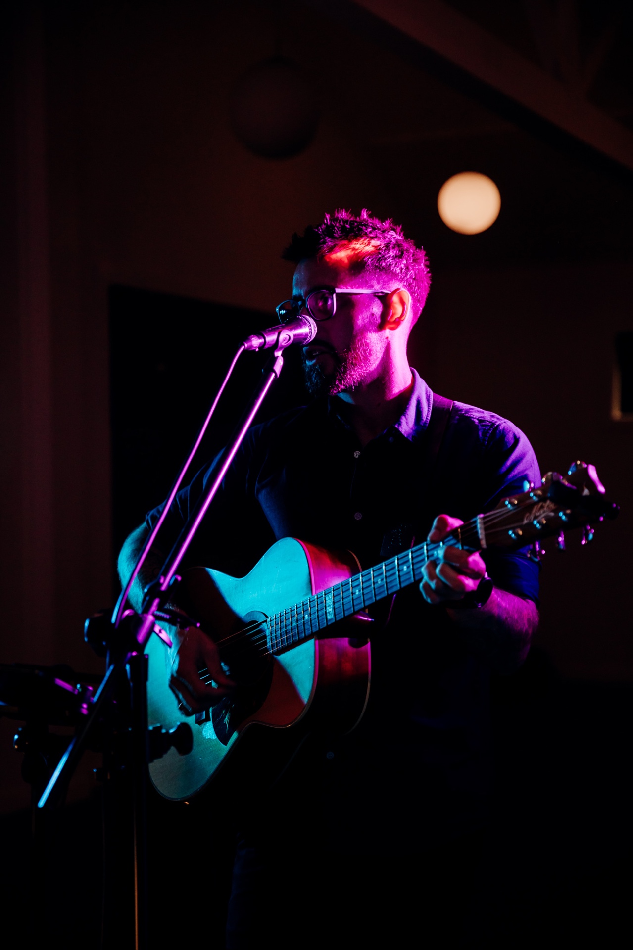 James Van performing live acoustic guitar under stage lights at an Auckland venue